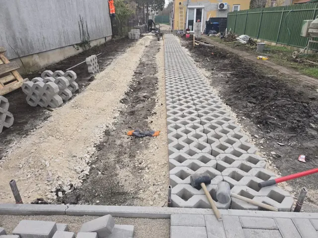 Beton gyeprácskő sávok fektetése zúzottkő alapra, előtérben térkő szegélysor
